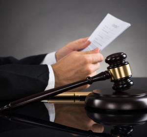 43938034 – close-up of judge holding document with gavel at desk